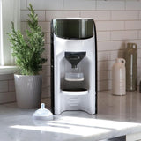 Automatic baby formula dispenser on a kitchen counter, ready to fill a bottle.