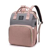 Pink and gray mommy diaper backpack featuring wide opening, large front pocket, and side USB charging port, front view.