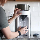 Parent using one-touch automatic formula maker to prepare a baby bottle.