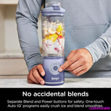 Hands pressing the blend button on a lavender cordless portable blender with fruit in the cup