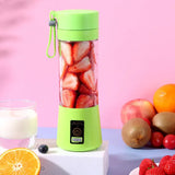 Green personal smoothie blender filled with strawberries on pink background with fresh fruit