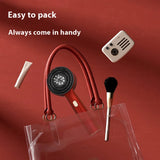 Red electric scalp massager in a travel flat lay with clear tote and beauty tools, portable size