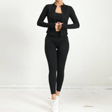 Woman in black yoga set with zip jacket and high-waist leggings, back view.
