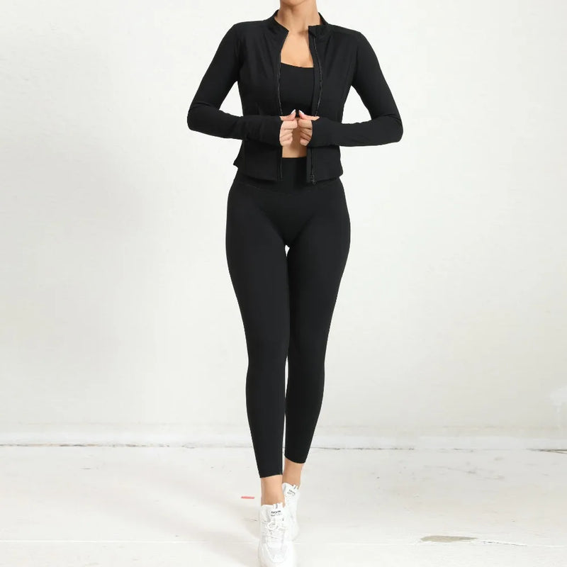 Woman in black yoga set with zip jacket and high-waist leggings, back view.